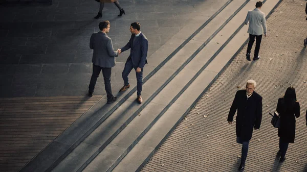 Gerentes de escritório e pessoas de negócios viajam para o trabalho pela manhã ou do escritório em um dia ensolarado a pé. Os pedestres estão vestidos de forma inteligente. Dois homens de negócios apertam as mãos. Tiro de cima . — Fotografia de Stock