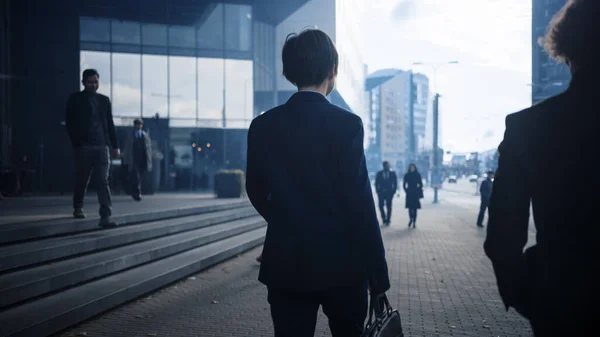 Businessman in a Suit Walking on the Street. Other Office People Commute to Work or Home. Its Early Morning or Late in the Evening. Back Shot. Urban City Lights in the Background. — Stock Photo, Image