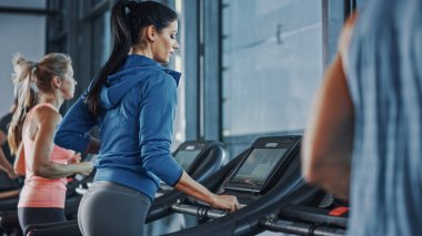 Koşu bandında koşan sağlıklı atletik kadın spor yapıyor. Kaslı Kadınlar ve Erkekler Modern Spor Salonu 'nda Aktif Eğitimdeler. Spor Salonu 'nda Spor İnsanları Antrenmanı. Yan Görünüm Görüntüsü