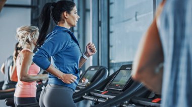 Koşu bandında koşan sağlıklı atletik kadın spor yapıyor. Kaslı Kadınlar ve Erkekler Modern Spor Salonu 'nda Aktif Eğitimdeler. Spor Salonu 'nda Spor İnsanları Antrenmanı. Yan Görünüm Görüntüsü
