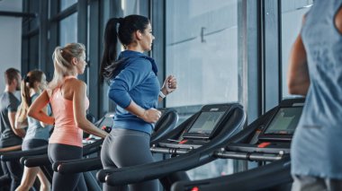 Koşu bandında koşan sağlıklı atletik kadın spor yapıyor. Kaslı Kadınlar ve Erkekler Modern Spor Salonu 'nda Aktif Eğitimdeler. Spor Salonu 'nda Spor İnsanları Antrenmanı. Yan Görünüm Görüntüsü