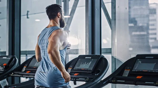 Koşu bandında Koşan Atletik Kaslı Adam, Bacak ve Kardiyo Günü. Modern Spor Salonu 'nda Güçlü Adam Eğitimi. Arka Görünüm Görüntüsü