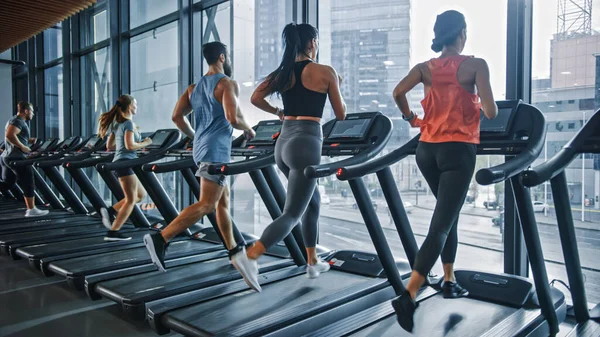 Gruppo di sei atleti che corrono sui tapis roulant, facendo esercizio di fitness. Donne atletiche e muscolari e uomini Allenamento attivo nella palestra moderna. Sport Persone Allenamento in Fitness Club. Vista laterale — Foto Stock