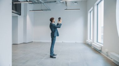 İşadamı Boş Ofiste Duruyor ve Tablet Bilgisayar 'daki Artırılmış Gerçeklik Yazılımıyla Haritasını Yapıyor. Girişimci Takım Elbise Giyer.