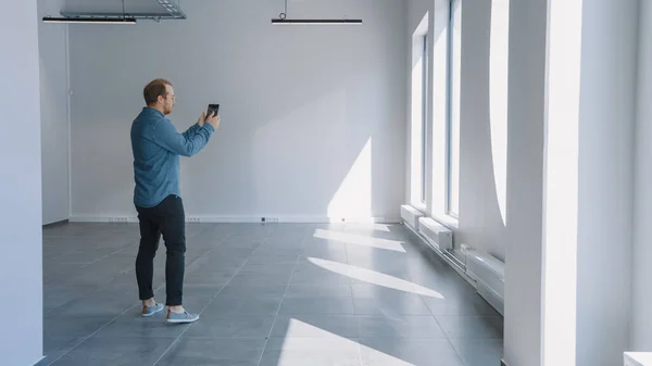 Young Hipster Man in Jeans Shirt Standing in Empty Office 그리고 향상 된 현실 소프트웨어로 지도를 만들었다. 큰 창문을 통해 빛 이비치다. — 스톡 사진