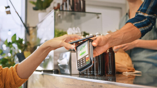 Young Woman is Using Contactless NFC Payment App Installed on Her Smartphone to Pay for Gourme Street Food. Eco Friendly Gluten Free Food Court Selling Modern Fusion Cuisine
