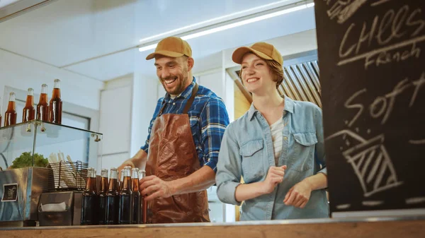 Sucesso Food Truck Trabalhadores masculinos e femininos em Brown Caps. Eles são alegres e sorridentes. Caminhão comercial ou quiosque que vende comida de rua e bebidas . — Fotografia de Stock