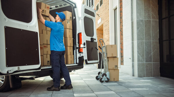 Delivery Man Uses Hand Truck Trolley Full of Cardboard Boxes and Packages, Loads Parcels into Truck Van. Professional Courier Loader helping you Move, Delivering Your Purchased Items Efficiently