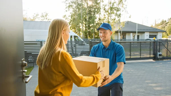 Hermosa mujer joven se encuentra con el hombre de entrega que le da su paquete de caja de cartón. Mensajero entregando paquete en el lindo barrio suburbano — Foto de Stock