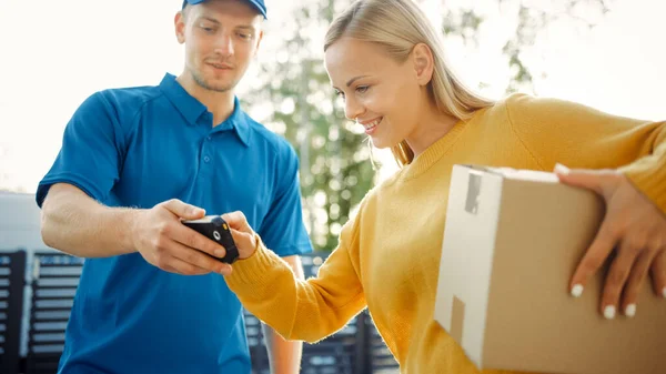 Hermosa mujer joven se encuentra con el hombre de entrega que le da su paquete de caja de cartón, que firma dispositivo de firma electrónica POD. Mensajero entregando paquete en el barrio de los suburbios . — Foto de Stock