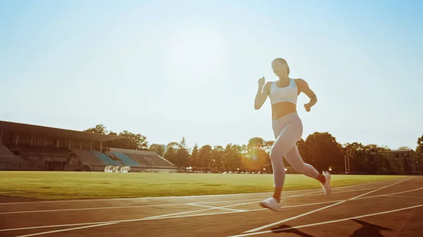 Belle fille de fitness en haut athlétique bleu clair et leggings jogging dans le stade. Elle court un après-midi d'été chaud. Athlète faisant son entraînement sportif de routine sur une piste. — Photo
