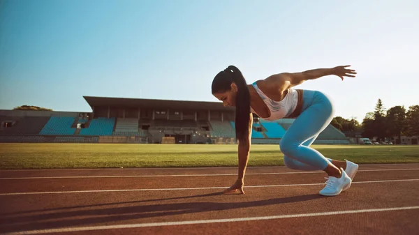 Mulher Fitness bonita em azul claro Atlético Top and Leggings está começando uma corrida de corrida de corrida em um estádio ao ar livre. Ela está correndo em um dia quente de verão. Atleta fazendo sua prática esportiva. — Fotografia de Stock