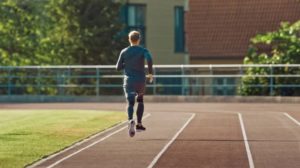 Smiling Athletic Fit Man in camicia grigia e pantaloncini da jogging nello stadio. Sta correndo veloce in un caldo pomeriggio d'estate. Atleta che fa la sua pratica sportiva di routine. — Foto Stock