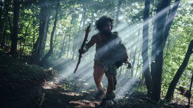 Hayvan Derisi Tutucu Taştan Mızraklı İlkel Mağara Adamı Etrafa Bakınıyor, Hayvan Avı Avında Tarih Öncesi Ormanı keşfediyor. Neanderthal Ormanda Avlanmaya Gidiyor