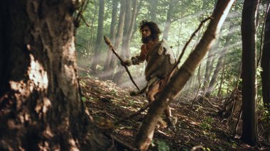 Hayvan Derisi Tutucu Taştan Mızraklı İlkel Mağara Adamı Etrafa Bakınıyor, Hayvan Avı Avında Tarih Öncesi Ormanı keşfediyor. Neanderthal Ormanda Avlanmaya Gidiyor