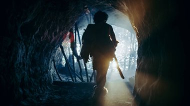 Hayvan derisi ve kürkü olan ilkel mağara adamı mağarasından çıkıp tarih öncesi ormanı avlamaya hazır hale geldi. Neanderthal Ormana Avlanmaya Gidiyor. Soğuk Filtreli Çekim.