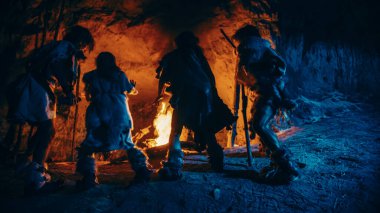 Tarih öncesi avcı-toplayıcı kabilesi geceleri mağaranın dışında şenlik ateşi etrafında dans eden hayvan derileri giyiyor. Neandertal Homo Sapiens Ailesi Pagan Dini Yapıyor Ateş Altında Dans Ediyor Yavaş Hareket