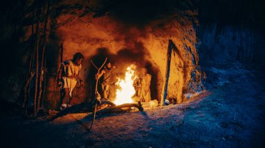 Tarih öncesi avcı-toplayıcı kabilesi hayvan derileri giyip geceleri mağaranın dışında şenlik ateşi etrafında dikiliyor. Neandertal Homo Sapiens Ailesi 'nin Pagan Dini Ayini Töreni