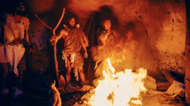 Tarih öncesi avcı-toplayıcı kabilesi hayvan derileri giyip geceleri mağaranın dışında şenlik ateşi etrafında dikiliyor. Neandertal Homo Sapiens Ailesi 'nin Pagan Dini Ayini Töreni