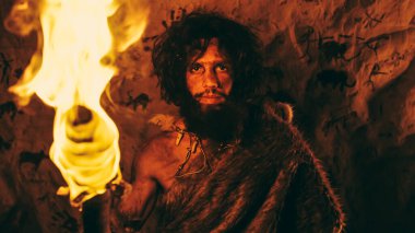 İlkel Mağara Adamı 'nın portresi Hayvan Derisi Giyen Gece Mağarasında Duran, Ateşli Meşale Tutan. İlkel Neandertal Avcı Homo Sapiens Gece Tek Başına. Arkaplanda Mağara Sanatı Çizimleri