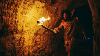 Primeval Caveman Wearing Animal Skin Exploring Cave At Night, Holding Torch with Fire Looking at Drawings on the Walls at Night. Neanderthal Searching Safe Place to Spend the Night clipart