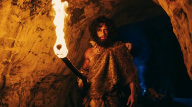 Hayvan derisi giyen ilkel mağara adamının portresi Gece vakti mağara keşfi, Ateşle Fener Tutmak Gece Kamerasına Bakmak.