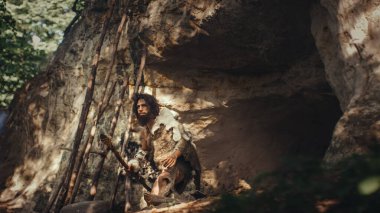 Hayvan derisi ve kürkü olan ilkel mağara adamı mağarasından çıkıp tarih öncesi ormanı avlamaya hazır hale geldi. Neanderthal Ormana Avlanmaya Gidiyor