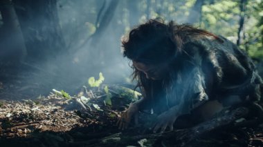 Tarih öncesi mağara kadını avcı-toplayıcı ormanda fındık ve dut arıyor. İlkel Neandertal Kadın Güneşli Ormanda Yiyecek Buluyor