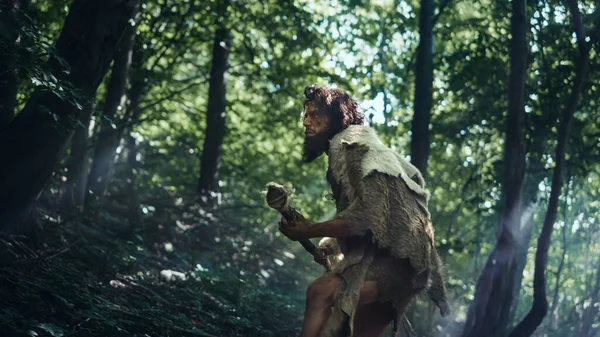 Porträtt av den primitiva grottmannen med djurhud och pälsjakt med ett stenspetsat spjut i den förhistoriska skogen. Förhistorisk neandertalare Scavenging med primitiva verktyg i djungeln — Stockfoto
