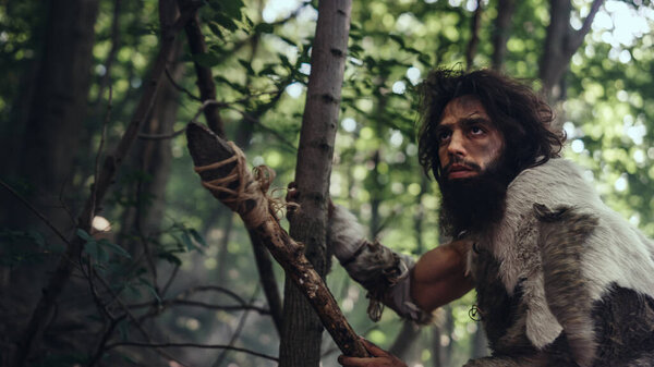Portrait of Primeval Caveman Wearing Animal Skin and Fur Hunting with a Stone Tipped Spear in the Prehistoric Forest. Prehistoric Neanderthal Hunter Ready to Throw Spear in the Jungle