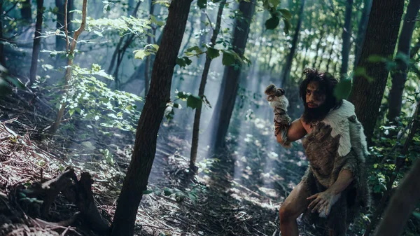 Portret van een oerholbewoner die dierenhuid en bontjacht draagt met een stenen speer in het prehistorische bos. Prehistorische Neanderthaler Hunter klaar om speer in de jungle te gooien — Stockfoto