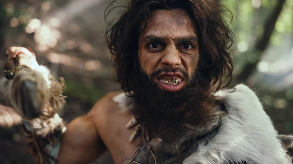 Porträtt av den primitiva grottmannen med djurhud och pälsjakt med ett stenspetsat spjut i den förhistoriska skogen. Förhistorisk neandertalare Skrik, hota och attackera — Stockfoto