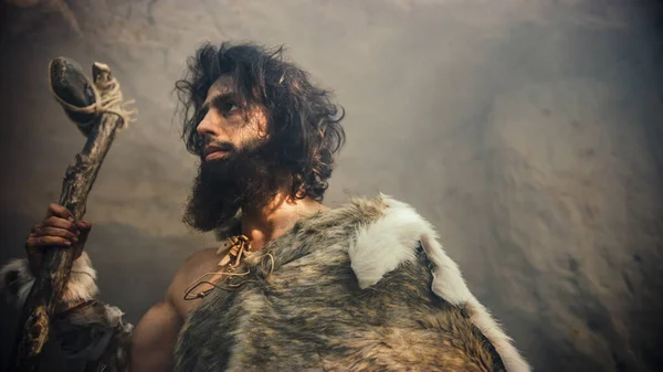 Primeval Caveman Wearing Animal Skin Holds Stone Tipped Hammer Comes out of the Cave and Looks into Prehistoric Forest, Ready to Hunt Animal Prey. Neanderthal Going Hunting into the Jungle. — Stock Photo, Image