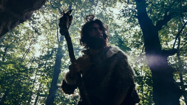 Silhouette of Primeval Caveman Wearing Animal Skin Holds Stone Hammer Looks Around Prehistoric Forest, Ready to Hunt Animal Prey. Neanderthal Going Hunting into the Jungle. Dramatic Low Angle Arc Shot — Stock Photo, Image