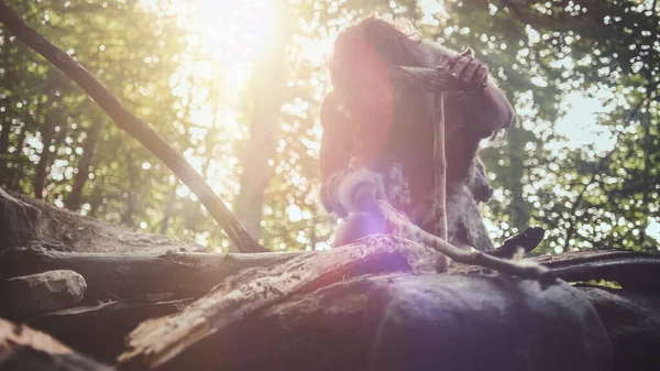 Silhouet van de oerholbewoner die dierenhuid draagt Probeert een vuur te maken met de Bow Drill Method. Neanderthaler Kindle Eerste door de mens gemaakt vuur in de geschiedenis van de menselijke beschaving. Lage hoek schot — Stockfoto