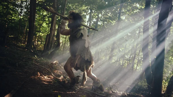 Tarih öncesi ormanda Hayvan Derisi Giyen İlkel Mağara Adamı 'nın Portresi ve Taş Ucu Mızrakla Kürk Avı. İlkel Neandertal Avcısı Ormana Mızrak Atmaya Hazır — Stok fotoğraf