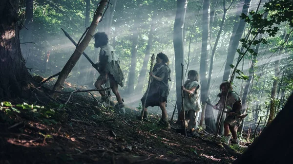 Tribe of Hunter-Gatherers Usando herramientas de punta de piedra para sujetar la piel de animales, explore el bosque prehistórico en una búsqueda de presas animales. Caza familiar neandertal en la selva o migración por una mejor tierra — Foto de Stock