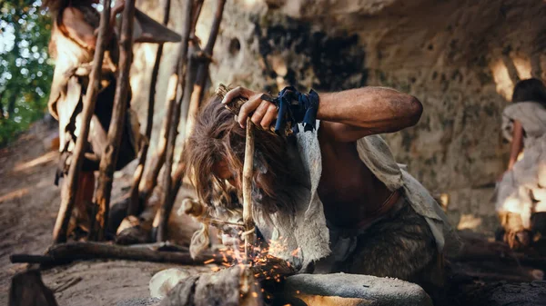 Primeval Caveman Wearing Animal Skin trying to make a Fire with Bow Drill Method 의 약자입니다. 네안데르탈인 킨들: 인간 문명의 역사에서 최초의 인간이 만든 불. 요리에 불을 붙이는 일. — 스톡 사진
