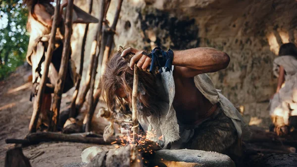 Hombre de las cavernas primitivo con piel de animal tratando de hacer un fuego con el método de taladro de arco. Neanderthal Kindle First Man-Made fire in the Human Civilization History (en inglés). Hacer fuego para cocinar . — Foto de Stock