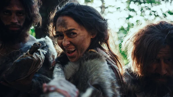 Leader femminile e due primitivi guerrieri delle caverne minacciano il nemico con la lancia di pietra ribaltata, urlano, difendendo la loro grotta e il loro territorio nei tempi preistorici. Neanderthal Homo Sapiens Tribù — Foto Stock