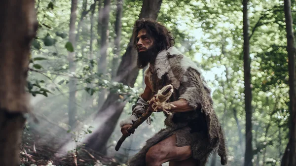 Primeval Caveman bär Animal Skin håller sten tippat spjut ser runt, utforskar förhistorisk skog i en jakt på djur byte. Neandertalarnas jakt i djungeln — Stockfoto