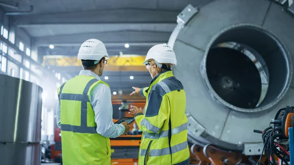 Zwei Schwerindustrie-Ingenieure stehen in der Rohr-Fertigungsfabrik, verwenden digitale Tablet-Computer, diskutieren. Fazilität für den Bau von Öl-, Gas- und Kraftstoffpipelines — Stockfoto