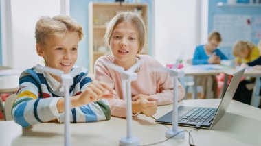 Liseli Kız ve Öğrenci Çocuk, Çevre ve Yenilenebilir Enerji hakkında bilgi edinmek için Rüzgâr Türbini Prototipi ile çalışıyor. Teknoloji üzerine çalışan çocukların olduğu ilköğretim okulu bilim sınıfı. STEM Eğitimi