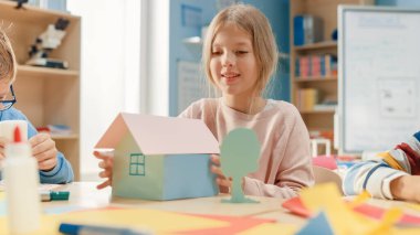 İlköğretim Okulu El Sanatları Sınıfı: Şirin Sarışın Kız El Sanatları Projesinde sınıf arkadaşlarıyla Eğlendi, Renkli Kağıt Kullanıyor, Bir Ev Yapıştırıcısı Kullanıyor