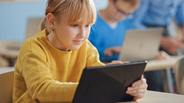 İlköğretim Okulu Bilgisayar Bilimi Sınıfı: Şirin Kız Dijital Tablet Bilgisayar kullanıyor, sınıf arkadaşları da dizüstü bilgisayarlarla çalışıyor. Çocuklar BTMM 'de Modern Eğitim Alırken, Oynarken ve Öğrenirken