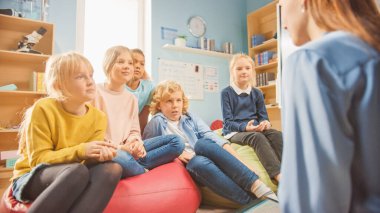 İlköğretim Okulu Yaratıcılık Sınıfı: Çocuklar halıda otururken Öğretmenler Dersi Açıklıyor. Modern Çevre 'de Akıllı Çocuklar Öğreniyor. Omzunun üstünden..