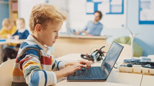 Young Schoolboy Uses Laptop to Program Software for Robotics Engineering Class 의 약자이다. 초등 학교 과학 교실 과 기품있는 똑똑 한 아이들 이 기술 과 함께 일하는 모습 — 스톡 사진