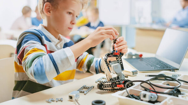Schoolboy Builds Constructs Small Robot and Uses Laptop to Program Software for Robotics Engineering Class. Elementary School Science Classroom with Gifted Brilliant Children Working with Technology