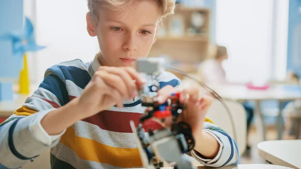 Ritratto Scatto di uno studente intelligente Costruisce un piccolo robot per la classe di ingegneria robotica. Scuola Elementare Science Classroom con i bambini brillanti dotati che lavorano con la tecnologia — Foto Stock