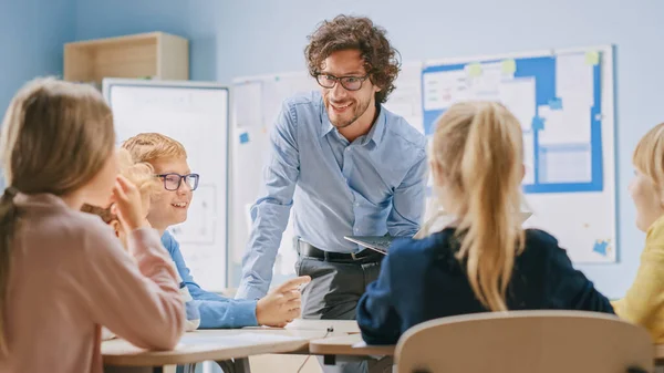 Enthusiastic Teacher elmagyarázza leckét egy osztályteremben tele fényes diverzifikált gyermekek, vezet osztály energetikus vita. Az Okos Többnemzetiségű Gyerekek Általános Iskolacsoportjában Új dolgokat tanulnak — Stock Fotó